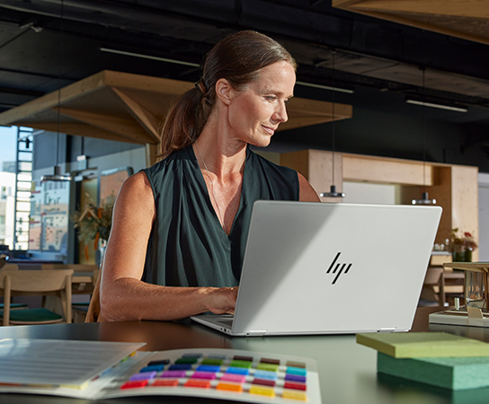 Fotografía de mujer trabajando en una laptop HP en su negoci...